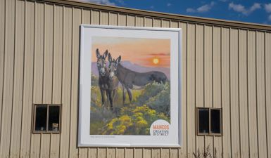 The current Mancos Creative District logo featuring burros on the side of the Mancos Chamber of Commerce building