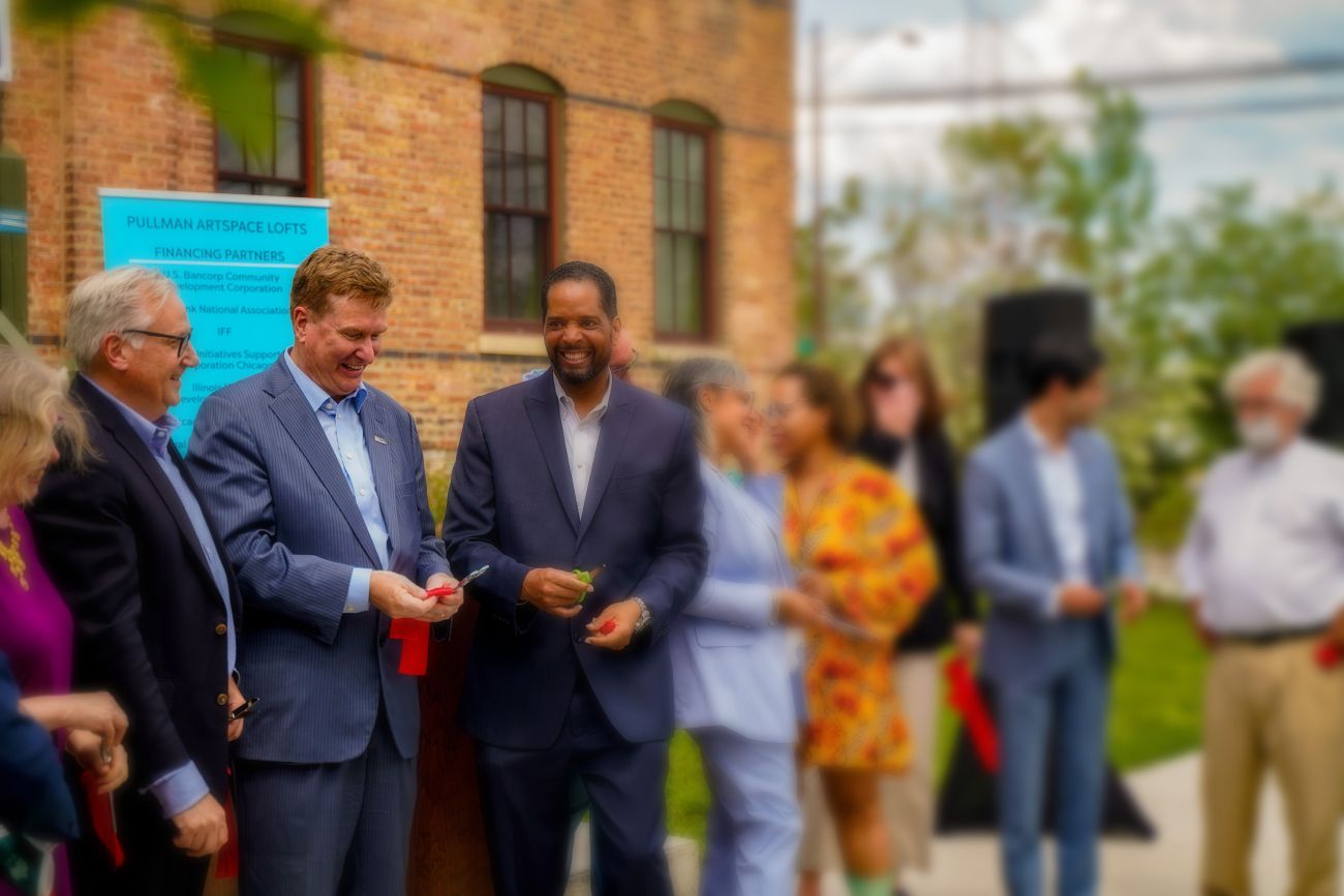 Terry Dolan at Ribbon cutting looking down on a ribbon smiling surrounding by other leaders of the project...