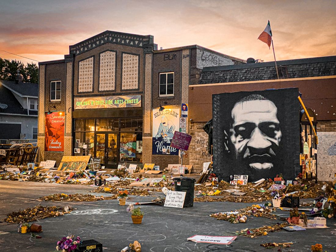 The front of the CAFAC building in the evening, in front of the building are flowers, art, flags, and candles to memorialize George Floyd who was wrongfully killed by Derek Chauvin, as proved in a court of law.