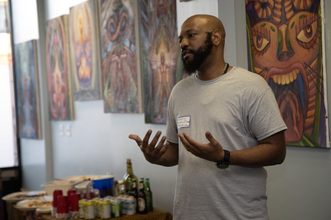 Speaker presenting in front of hanging artwork.