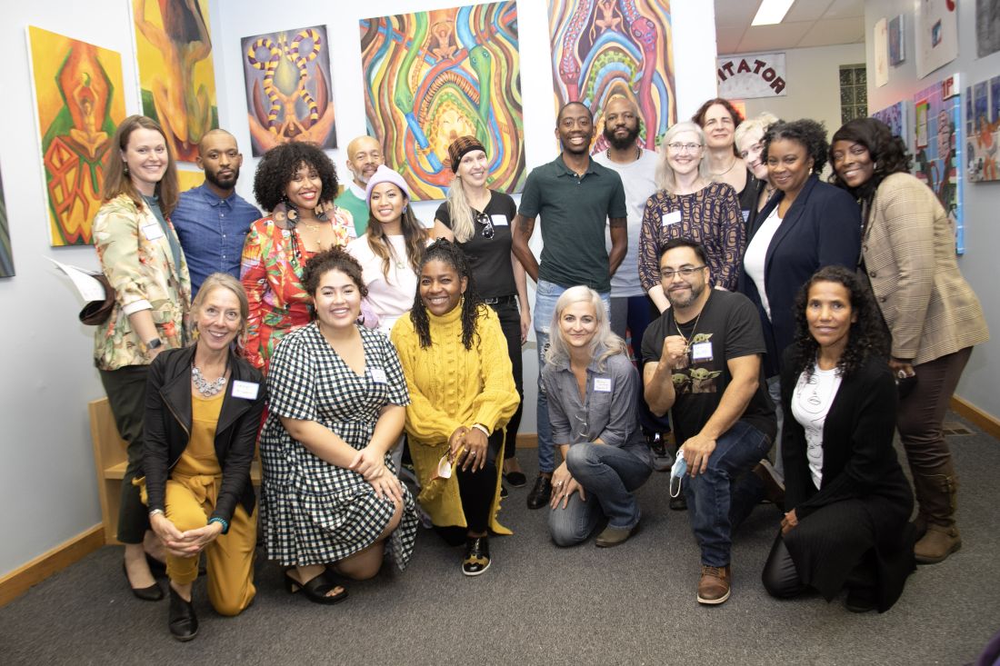 The group posing together with some artwork hanging behind them.