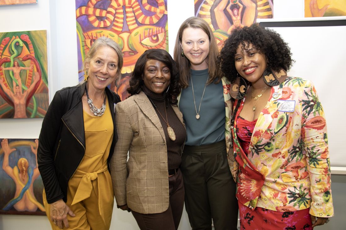 The group posing together with some artwork hanging behind them.