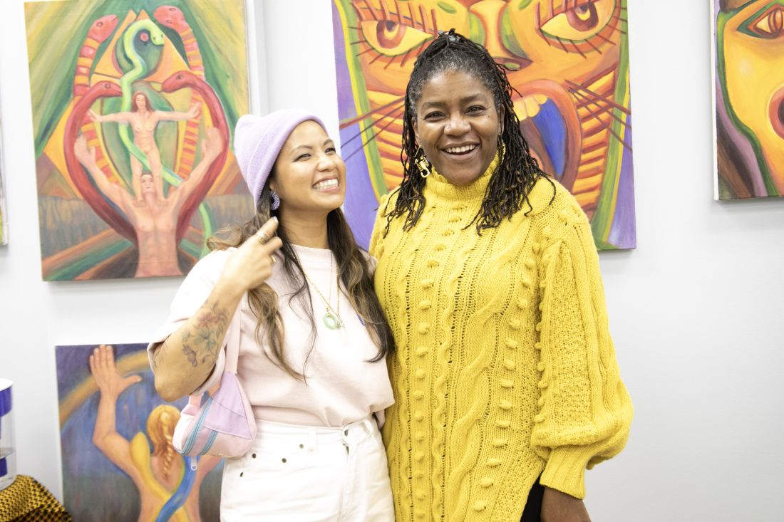 Posing together in front of paintings.