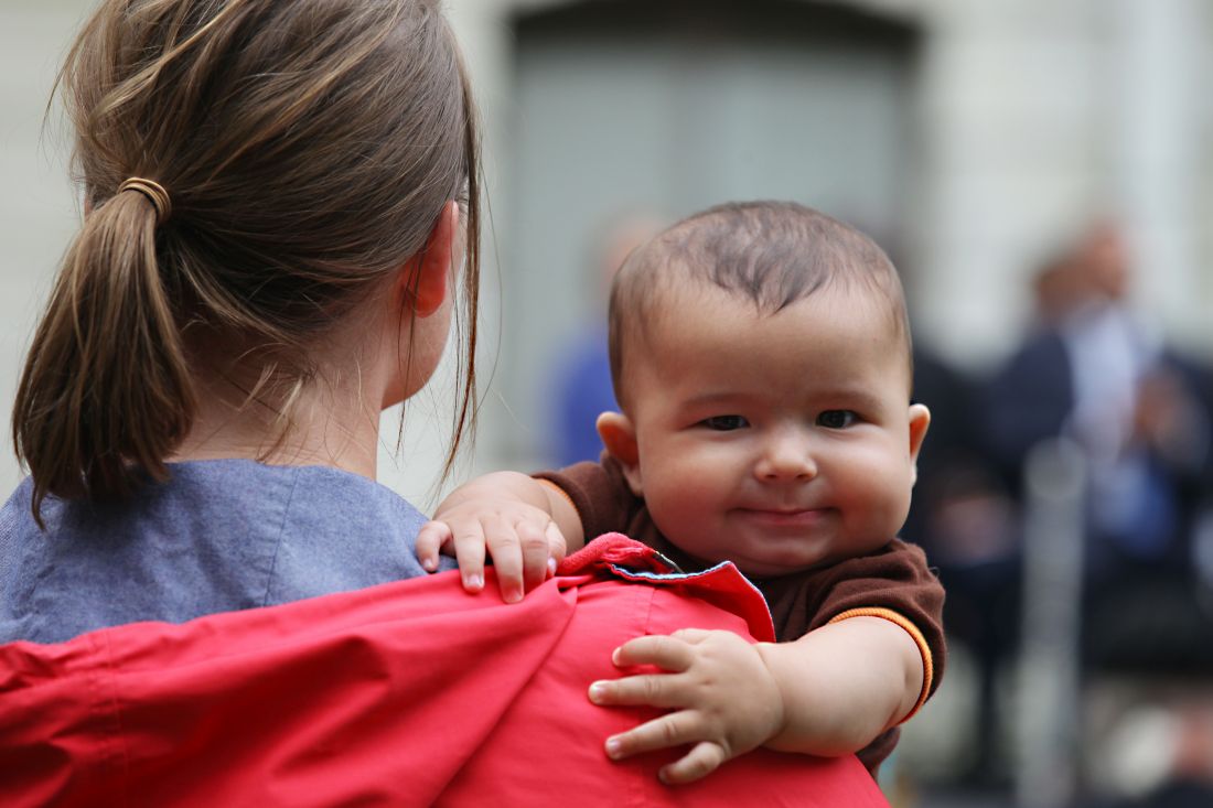 A baby and caretaker watching the groundbreaking ceremony.