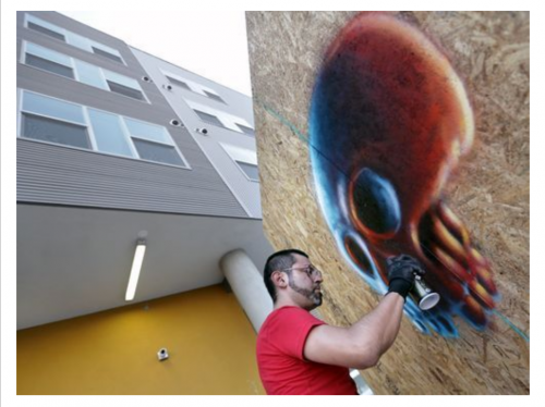 Artist spraypainting a giant skull.