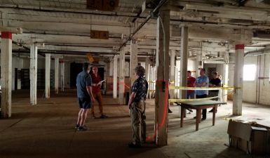 Two people stand in an empty basement space