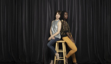 two dancers, sitting back-to-back