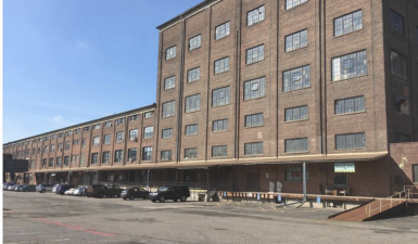 an image of the Northrup King  Commercial building from the parking lot on a sunny day. There is a vibrant blue sky behind it.