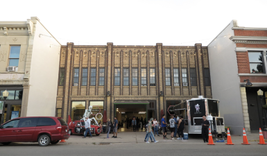 exterior of the. building during the celebration* there are food trucks outside with a crowd lots of activity.