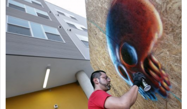 Artist spraypainting a giant skull.